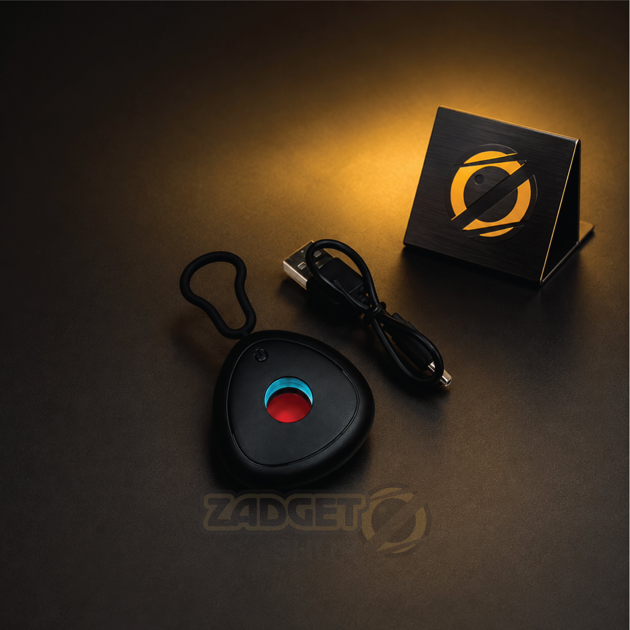 Black rechargeable hidden camera detector with carrying loop and USB cable on dark background